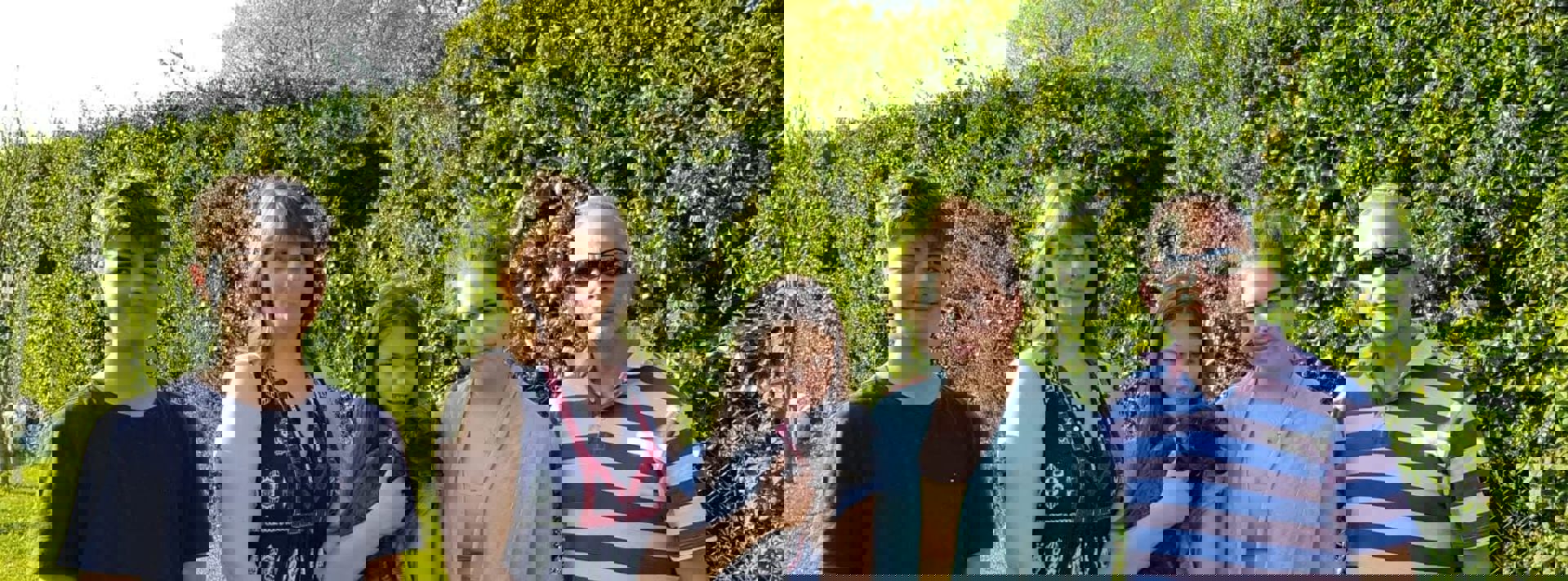 A family and their dog stood in a garden against a green hedge A family and their dog stood in a garden against a green hedge
