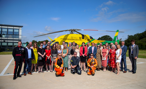 A photo of the Coombe Castle team by the wiltshire air ambulance aircraft on a sunny day