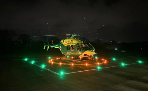 Wiltshire and Bath Air Ambulance Charity's new look helicopter on their helipad at night with the lights on